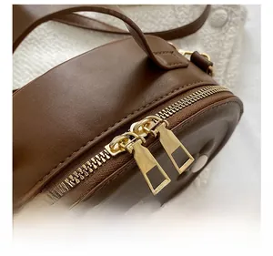 Gros plan d'un sac en cuir PU marron foncé avec détails de double fermeture éclair dorée