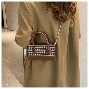 Close-up of mini houndstooth crossbody bag with brown leather handles and silver bead chain