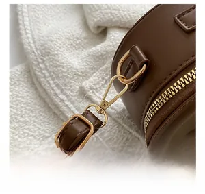 Vue détaillée du sac rond en cuir marron avec crochets en métal doré et anneau en D