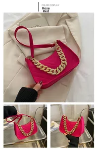 Detail of rose red baguette bag with V-shaped quilting and chunky gold chain strap