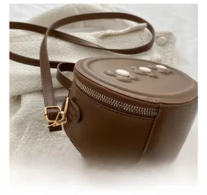 Détail d'un sac rond en cuir PU marron pour enfants avec fleurs marguerites gaufrées