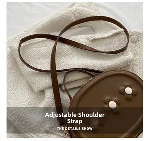 Détail de la bandoulière réglable et des fleurs 3D sur le sac marron en cuir synthétique