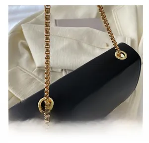 Detail of the golden metal grommets and elegant square chain on a black leather crossbody bag