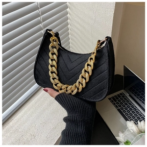 Close-up of black felt hobo bag with V-shaped quilting and a gold chain strap