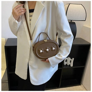 Détail d'un sac à main ovale en cuir PU marron pour enfant avec trois fleurs blanches