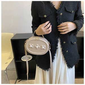 Détail d'un sac bandoulière beige en similicuir avec trois fleurs 3D et fermoirs dorés