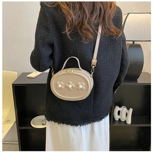 Vue détaillée du mini sac bandoulière beige avec fleurs 3D porté sur une veste en tweed