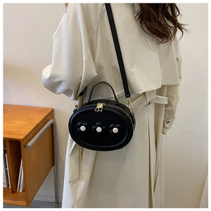 Détail d'un sac bandoulière noir pour filles avec fleurs 3D et fermeture éclair dorée