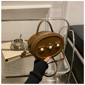 Détail du mini sac à bandoulière en cuir PU marron avec fleurs sur une table basse en verre