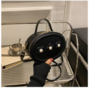 Détail d'un mini sac en cuir noir avec fleurs blanches et fermetures éclair dorées