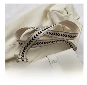 Détail du sac bandoulière crème avec boucle H dorée et bandoulière en tissu tressé