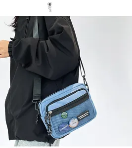 Detail of light blue crossbody nylon bag featuring mesh pocket and sports utility style