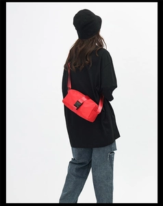 Detail view of red oxford cloth crossbody bag with black buckle and adjustable strap