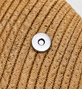 Gros plan du fermoir magnétique en métal argenté sur la texture du sac en paille