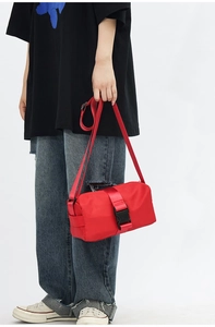 Detail view of red oxford fabric crossbody bag featuring a large black plastic buckle