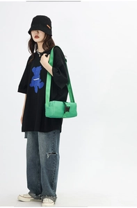 Neon green nylon crossbody bag with black buckle closure worn in street style look