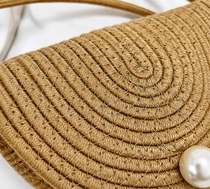 Détail du sac en paille tressée montrant la texture spirale et les perles décoratives