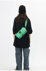 Detail view of a bright green waterproof nylon crossbody bag with black buckle strap
