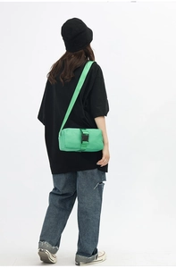 Detail of green nylon canvas crossbody bag with black buckle on street style model