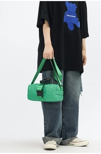 Detail of a bright green cylinder nylon crossbody bag with buckle and shoulder strap