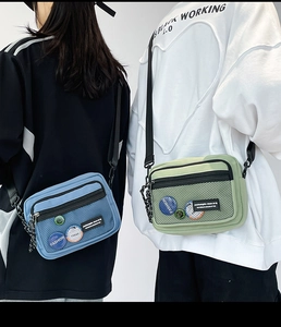 Detail view of blue and green canvas crossbody bags with mesh pockets and adjustable straps
