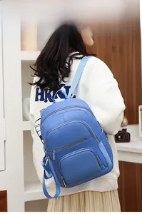 Detail view of water-resistant light blue nylon backpack with multiple zipper pockets