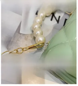 Close-up of light green quilted jelly bag with pearl handle and golden chain details