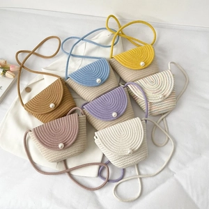Sacs à bandoulière tissés avec bouton perle en plusieurs couleurs sur une surface blanche