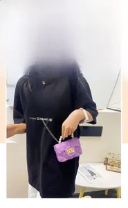 Detail of purple quilted mini bag featuring pearl handle and golden chain strap