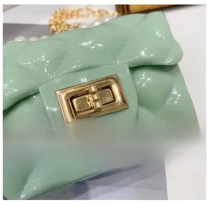 Detail of mint green quilted jelly bag featuring a gold clasp and pearl chain strap