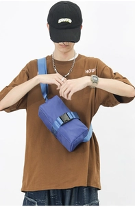 Detail of blue nylon crossbody bag with black plastic buckle and waterproof texture