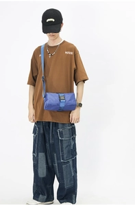 Detail of bright blue oxford fabric crossbody bag with black plastic buckle and strap