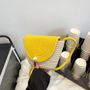Détail de la texture tissée jaune et blanc avec une grande perle décorative sur le rabat