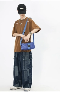 Detail of bright blue nylon crossbody bag with wide strap and black plastic buckle