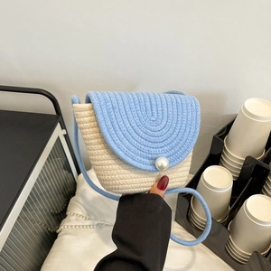 Détail du sac en paille tissé à la main avec contraste bleu ciel et grand bouton perle
