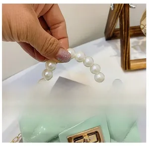 Detail of mint green quilted mini bag featuring pearl handle and gold chain strap hook