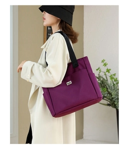 Vue détaillée du sac cabas en nylon violet avec poches latérales et logo sur modèle
