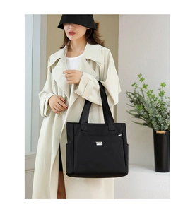 Sac fourre-tout chic en nylon noir porté par un mannequin en trench-coat beige élégant