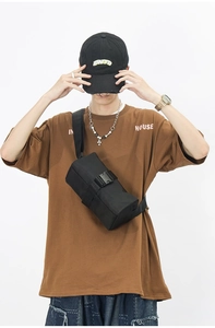 Detail of durable black nylon crossbody bag with robust plastic buckle on white background