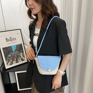 Détail du sac à bandoulière en paille tressée avec rabat bleu orné d'une perle