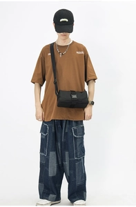 Detail of black oxford nylon crossbody bag with plastic buckle closure on male model