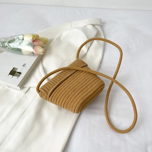 Vue de dessus d'un mini sac bandoulière jaune tissé main sur blazer blanc et tulipes