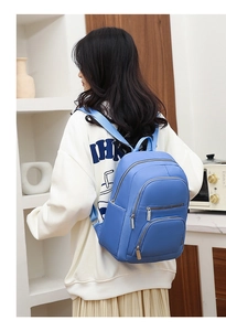 Detail of bright blue faux leather backpack showing triple zipper pockets and straps