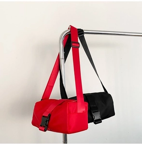 Detail of red and black cylindrical crossbody bags with buckle closure and nylon straps