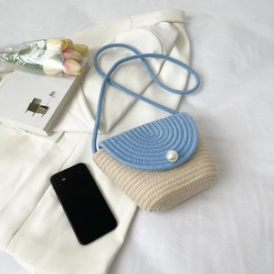 Détail du sac tressé bleu et beige avec boucle perle et décoration florale élégante