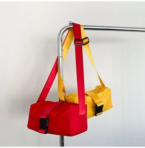 Detail of red and yellow oxford crossbody bags with plastic buckles and wide straps