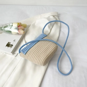 Détail du sac bandoulière tressé avec rabat bleu clair et texture paille élégante