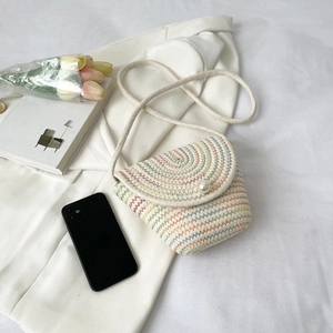 Détail d'un sac en paille tissée avec motif zigzag coloré et fermeture bouton perle