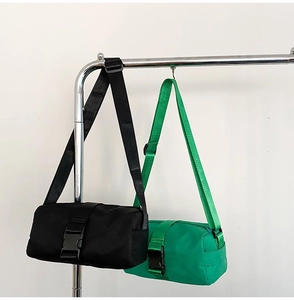 Detail view of cylindrical nylon crossbody bags in black and neon green with buckles