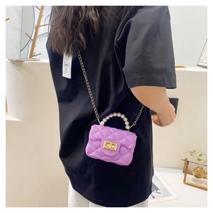 Detail of purple jelly bag with quilted texture, pearl handle and gold chain strap